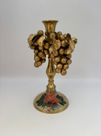 Brass candle holder with grape design on a white background