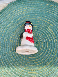 Small snowman figurine on a textured green surface