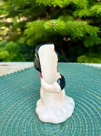 Figurine on a textured surface with greenery in the background