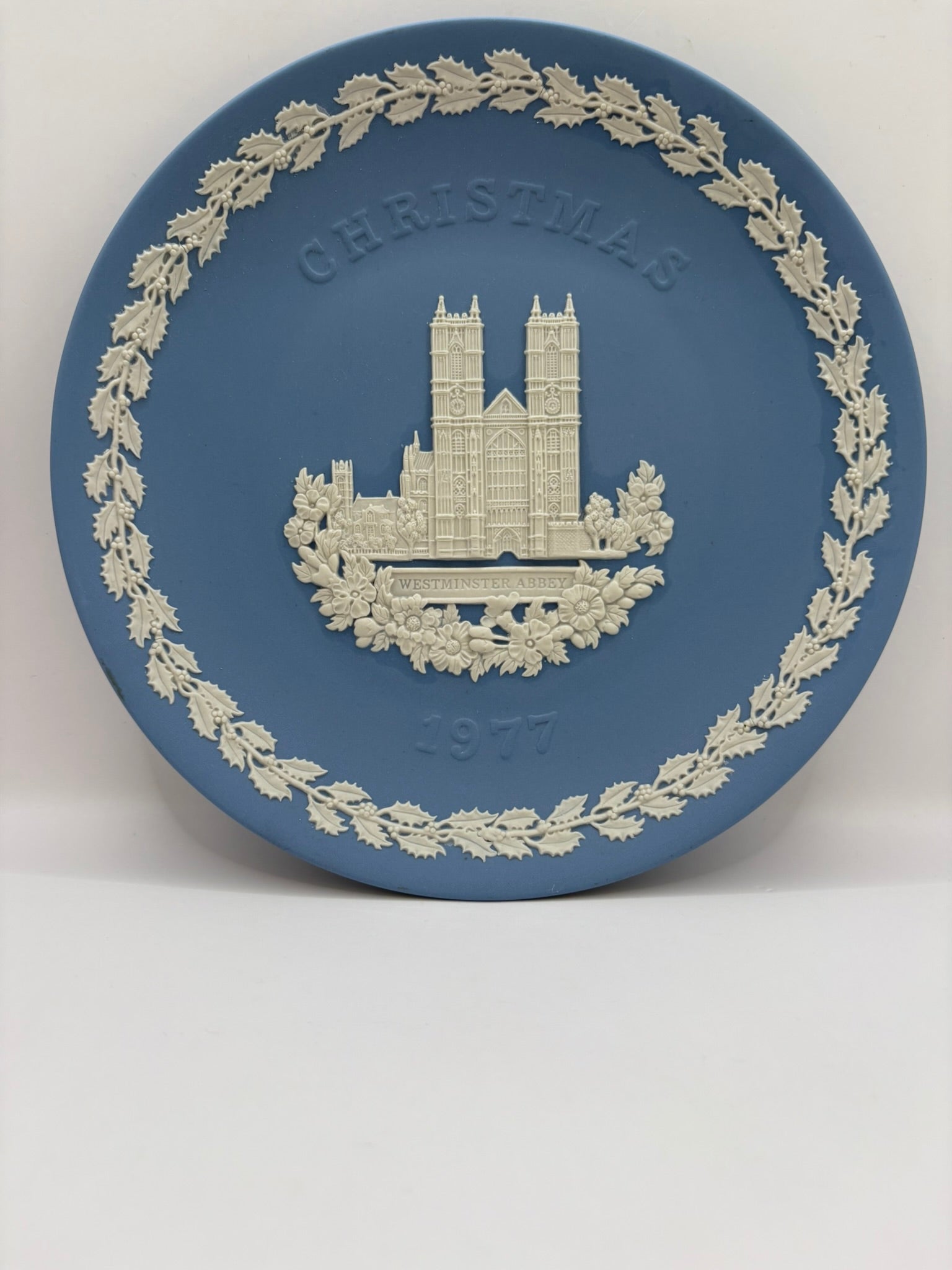 Decorative plate with a Christmas design featuring a building and wreath on a blue background