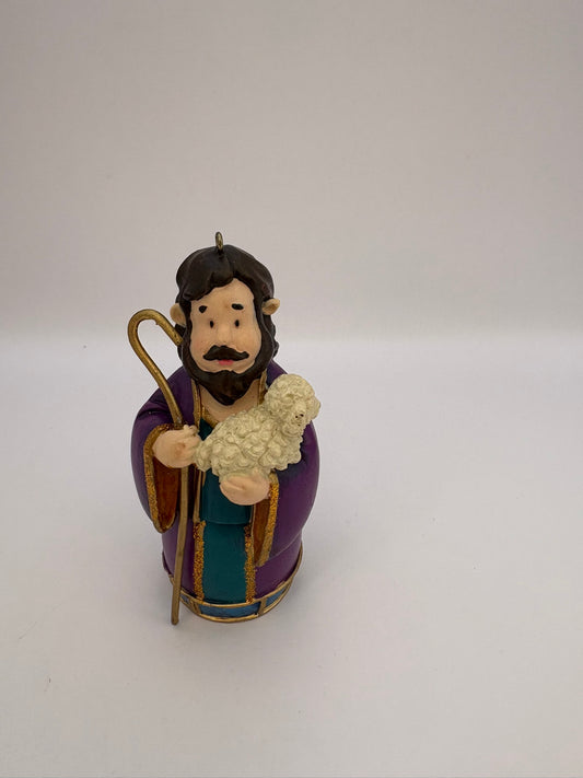 Figurine of a shepherd holding a lamb on a white background