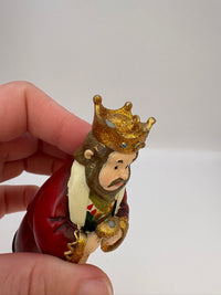 Small figurine of a king with a crown held by a hand against a white background