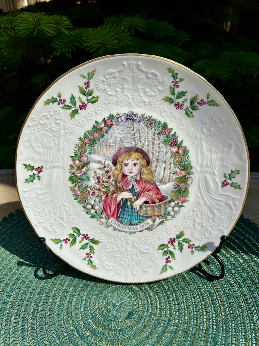 Decorative plate with a girl in a red coat and plaid skirt on a green textured surface.