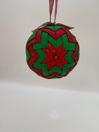 Round woven ornament with red and green pattern on a white background