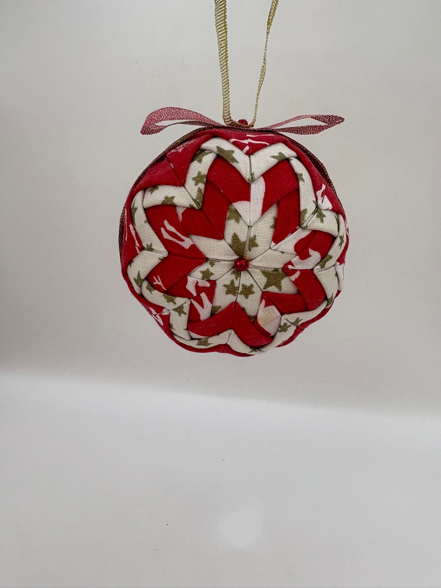 Heart-shaped fabric ornament with red and white pattern on a plain background