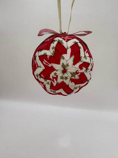 Heart-shaped fabric ornament with red and white pattern on a plain background