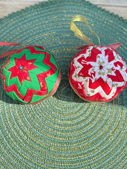 Two decorative Christmas balls with floral patterns on a textured green surface.