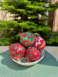 Decorative Christmas balls on a plate with a Christmas tree in the background