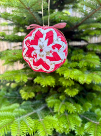 Decorative red and white ornament hanging on a Christmas tree.