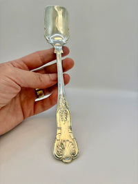 Silver spoon held by a hand on a plain background