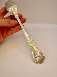 Hand holding a decorative silver spoon against a plain background