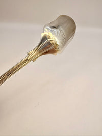 Decorative silver spoon with gold handle on a light gray background
