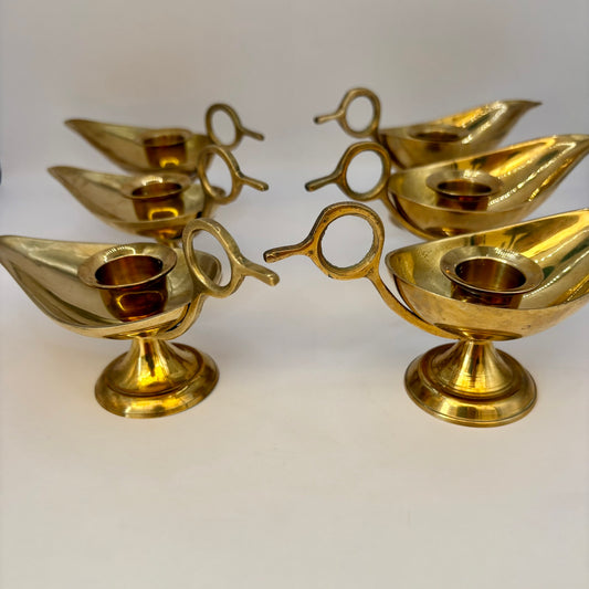 Set of four brass candle holders on a white background