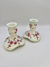Two ceramic candle holders with floral designs on a white background