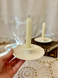 White ceramic candle holder with a candle on a lace tablecloth