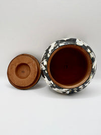 Ceramic jar with black and white patterned lid on a white background