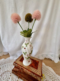 Decorative vase with flowers on a stack of books against a white curtain background