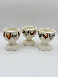 Three ceramic egg cups with chicken illustrations on a white background