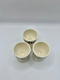 Three ceramic cups with floral patterns on a white background