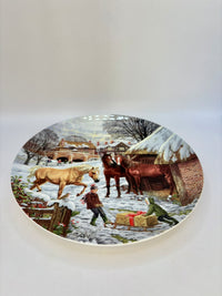 Decorative plate with a winter scene featuring people and animals.