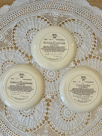 Three decorative plates with text on a lace tablecloth