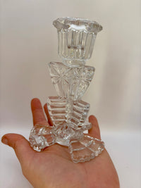 Clear glass candle holder held in a hand against a white background