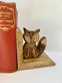 Wooden fox bookend next to a red book on a white background