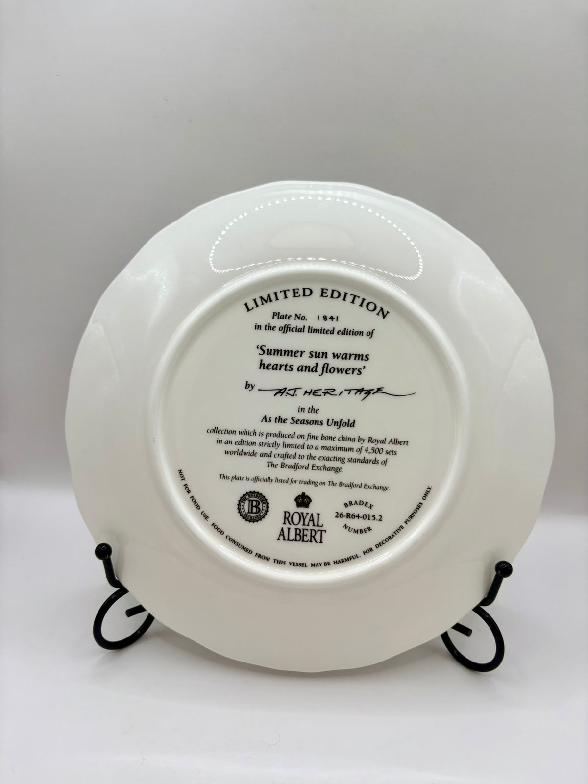 White decorative plate with text and branding on a stand against a white background