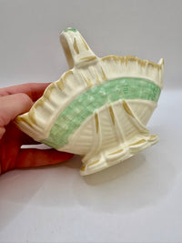 Ceramic leaf-shaped dish with green interior held by a hand on a white background