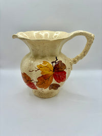 Ceramic pitcher with autumn leaf design on a white background