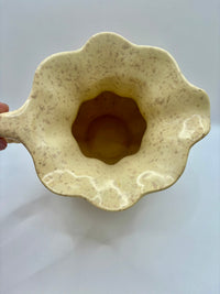 Beige ceramic scoop with scalloped edge on a white background