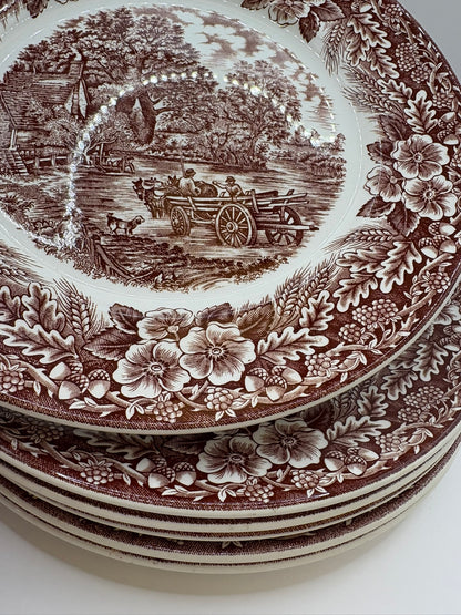 Stack of decorative plates with brown transferware design on a white background