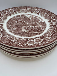Stack of decorative plates with brown transferware design on a white background
