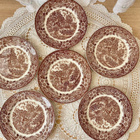 Set of six brown transferware plates on a lace doily