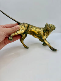 Gold dog figurine held by a hand on a white background