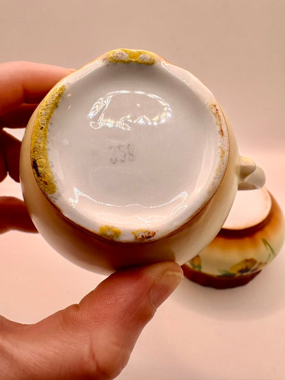 Ceramic cup with chipped glaze held by a hand against a neutral background