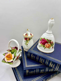 Decorative items including a small bell, flower-shaped container, and books with floral designs on a white background.