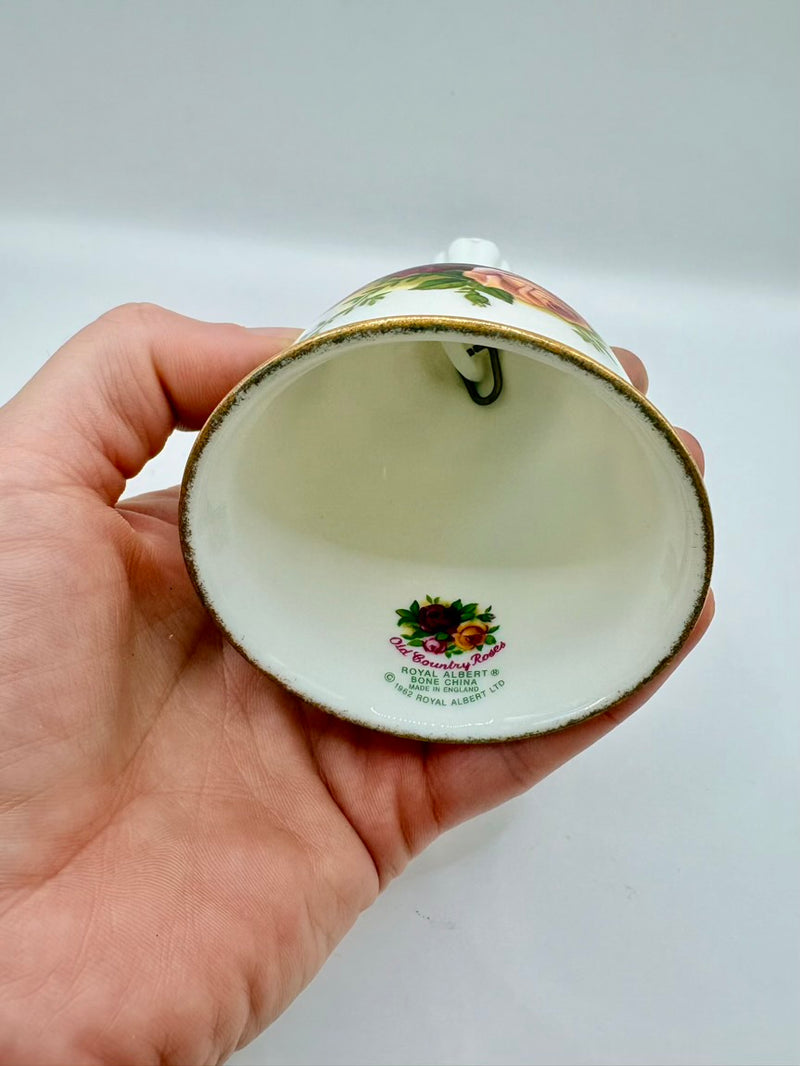 Hand holding a decorative ceramic item with floral design on a plain background