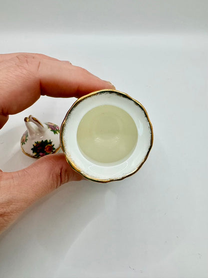 Hand holding a small ceramic cup with a white interior on a plain background