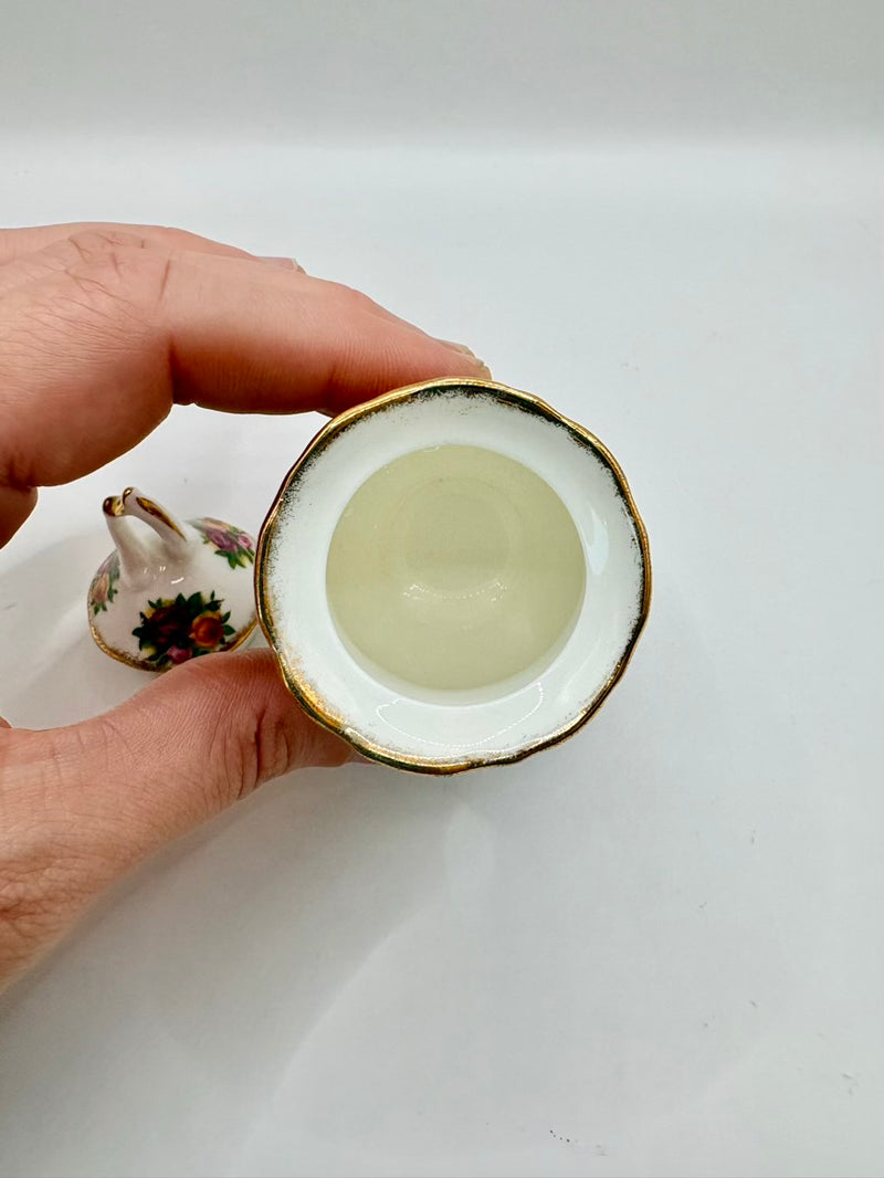Hand holding a small ceramic cup with a white interior on a plain background