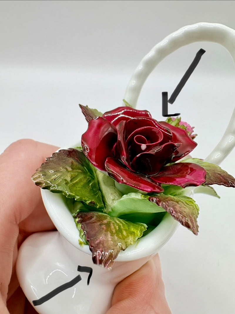 Artificial flower arrangement in a white ceramic holder with a clock background