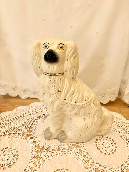White ceramic dog figurine on a lace tablecloth with a white curtain background