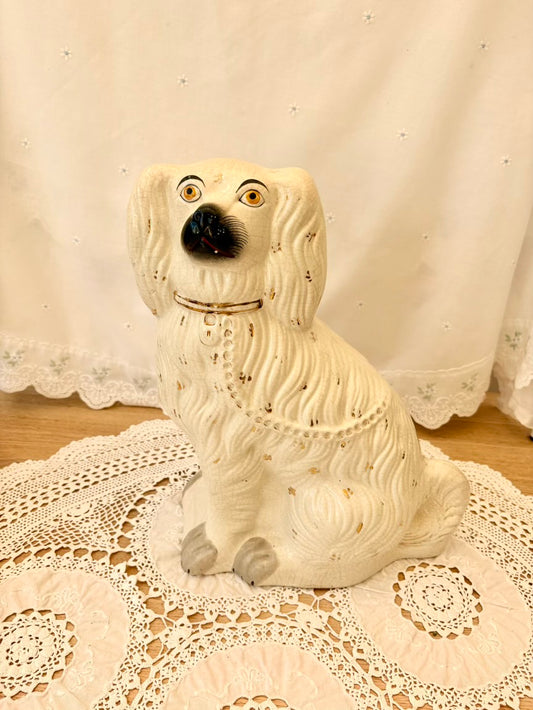 White ceramic dog figurine on a lace tablecloth with a white curtain background