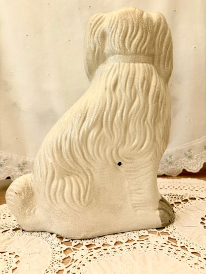 White ceramic dog figurine on a lace tablecloth with a neutral background