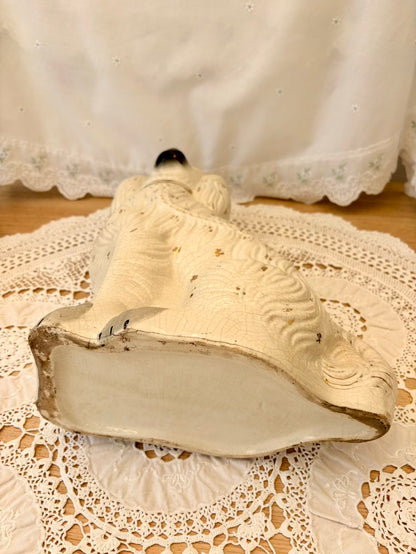Decorative white iron on a lace doily with a white curtain in the background