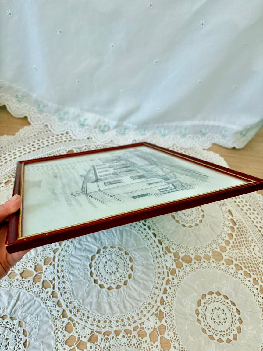 Framed black and white drawing held over a lace tablecloth