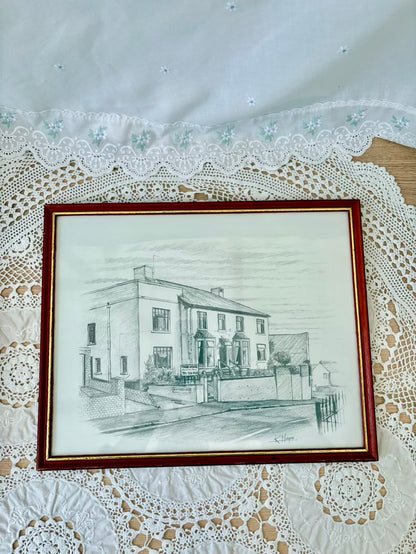 Framed pencil drawing of a house on a lace tablecloth