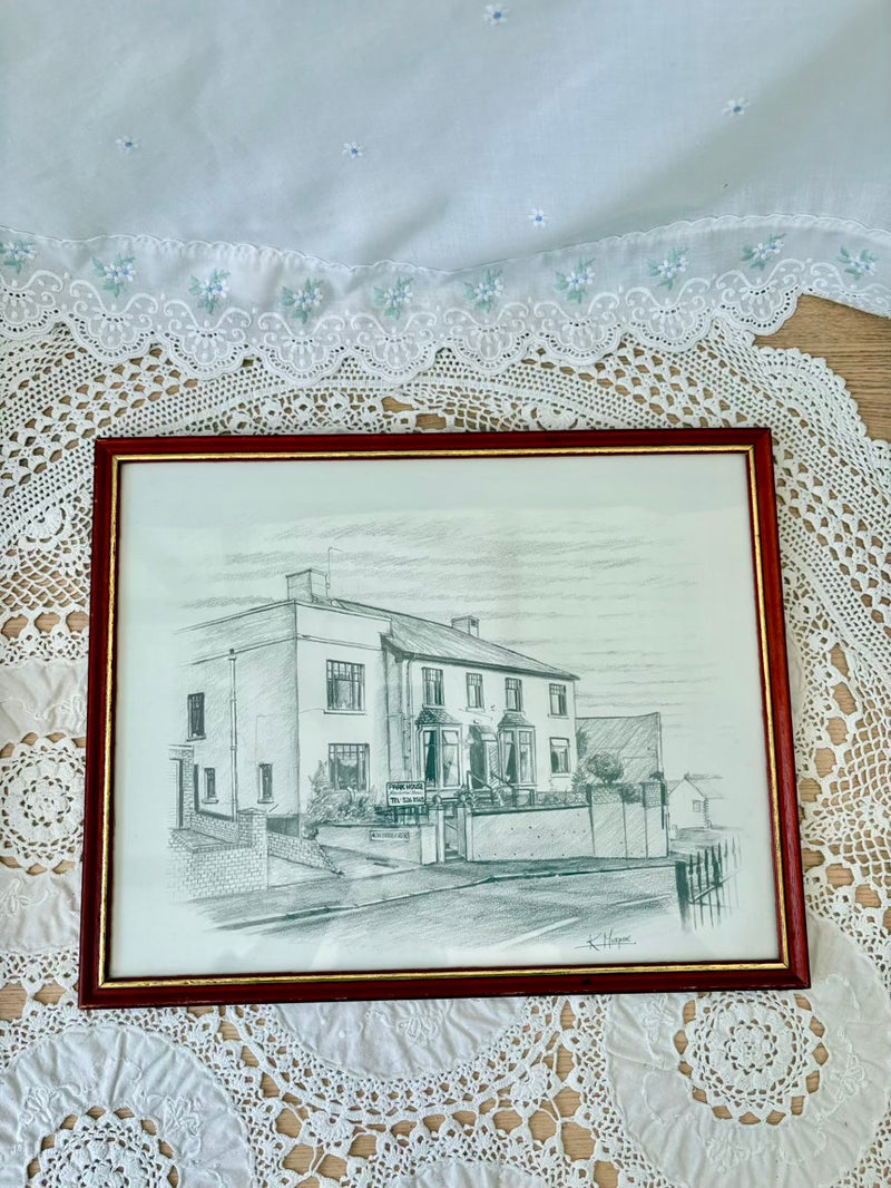 Framed pencil drawing of a house on a lace tablecloth