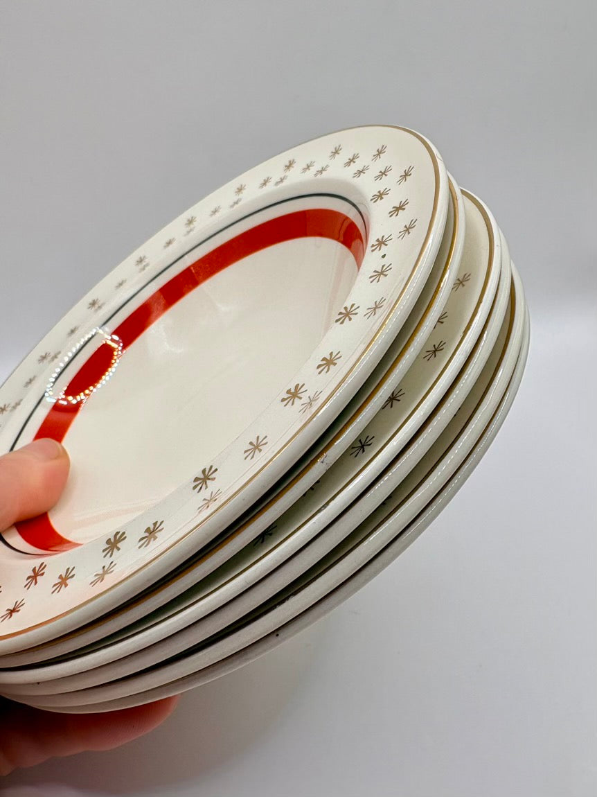 Stack of ceramic plates with decorative rim held by a hand on a gray background