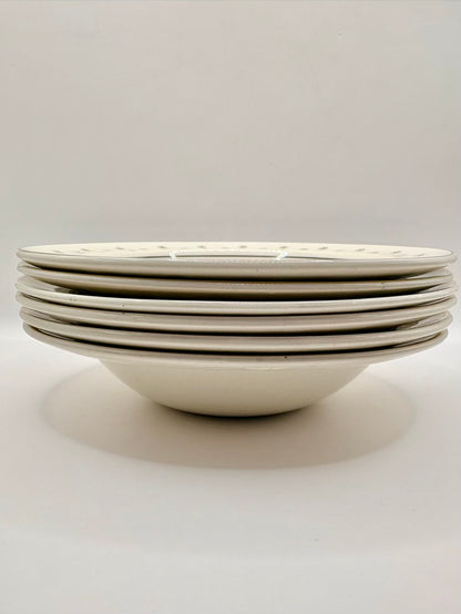 Stack of white ceramic bowls with black rim on a light gray background